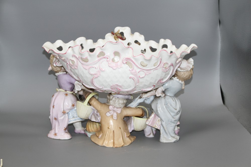 An early 20th century German porcelain centrepiece, with floral encrusted bowl supported by three children, height 28.5cm, width 44cm